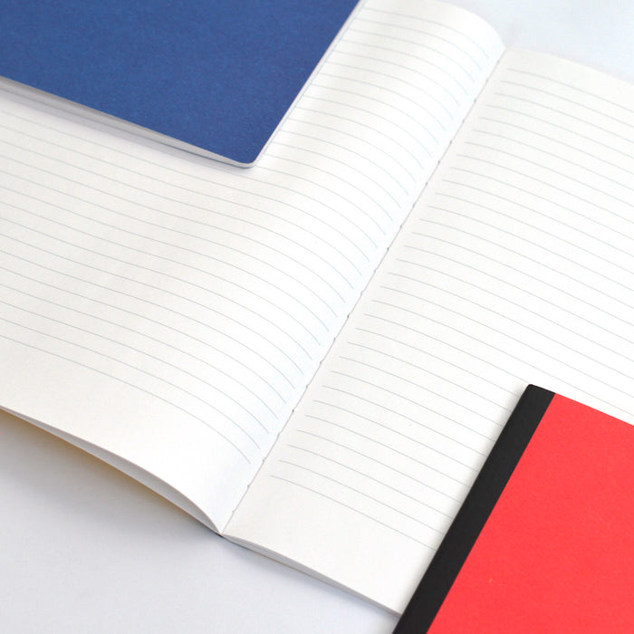 Close-up of large lined notebook pages with colorful blue and red Ameico covers, showcasing minimalist journals with clean ruled paper for writing and note-taking.