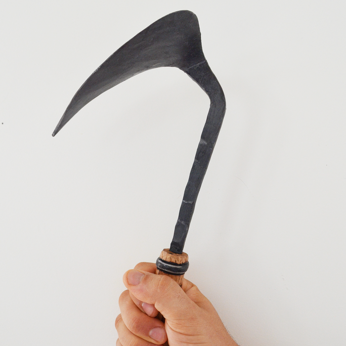 Hand holding a sickle against a white background