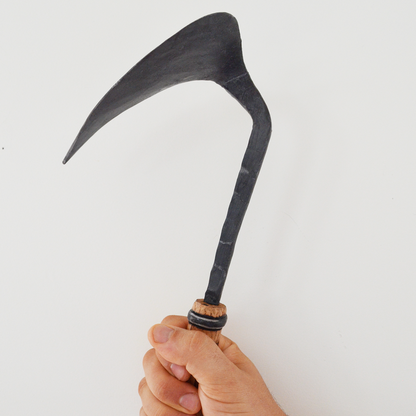 Hand holding a sickle against a white background