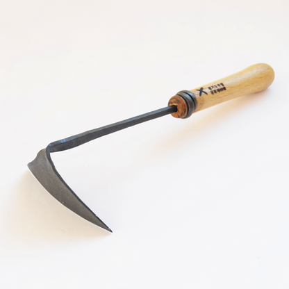 Hand-forged winged garden hoe with a curved dark steel blade and light wooden handle, displayed on a clean white background in a minimalist artisan gardening product presentation.