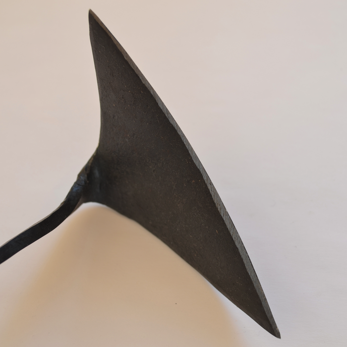 Close-up side view of a hand-forged winged garden hoe blade in dark steel, displayed on a clean white background to highlight its sharp edge and artisan craftsmanship.