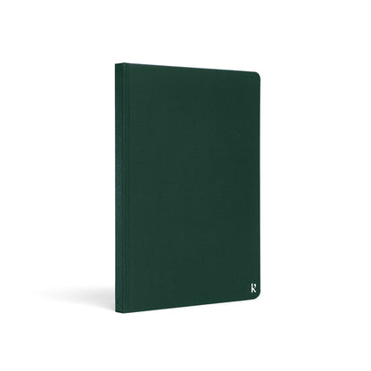 Karst A5 hardcover stone paper notebook in forest green with rounded corners and subtle logo detail, standing upright on a light gray background.