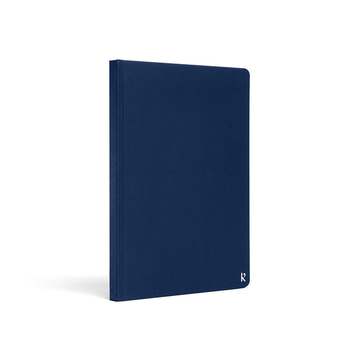 Karst A5 hardcover stone paper notebook in navy blue with rounded corners and subtle logo detail, standing upright on a light gray background.
