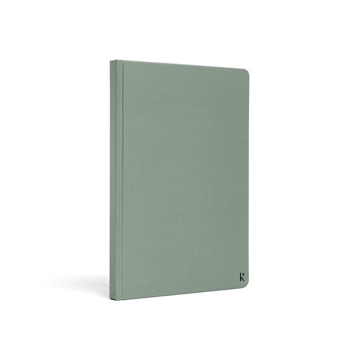 Karst A5 hardcover stone paper notebook in eucalyptus green with rounded corners and subtle logo detail, standing upright on a light gray background.