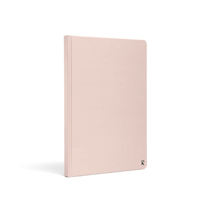 Karst A5 hardcover stone paper notebook in blush pink with rounded corners and subtle logo detail, standing upright on a light gray background.