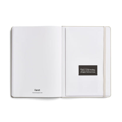 Inside back pages of a Karst A5 stone paper notebook, shown open with a blank page, elastic closure band, and a branded message card reading ‘Take note today, shape tomorrow’ on a white background.