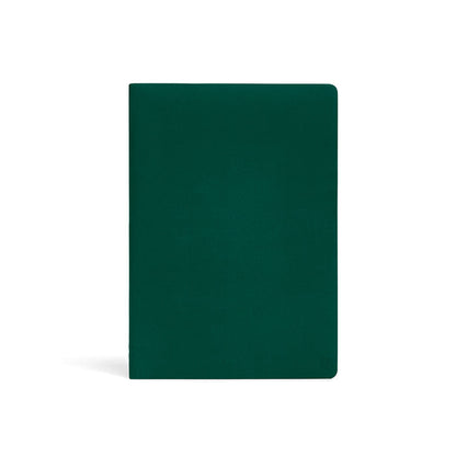 Karst A5 softcover stone paper notebook in forest green with rounded corners and subtle embossed logo, standing upright on a light gray background.