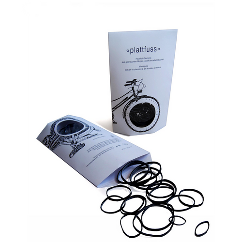 Black household rubber bands made from recycled bicycle and moped inner tubes, shown loose and in minimalist retail packaging for eco-friendly office, kitchen, and everyday organization.