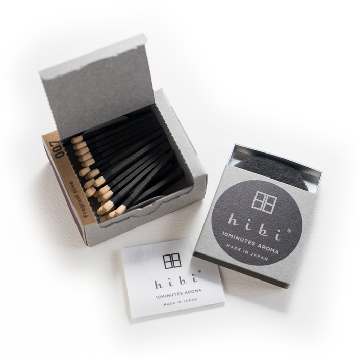 Open hibi 10 Minutes Aroma incense matchbox showing black incense matches, striker pad, and Fragrant Olive packaging on a white background.