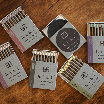 Assorted hibi 10 Minutes Aroma incense matches displayed on a wooden surface, showing multiple scents in open and closed boxes