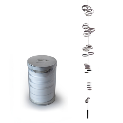 White paper ring hanging mobile shown fully assembled beside its cylindrical package, minimalist kinetic decor with floating circular elements for modern home or office interiors.