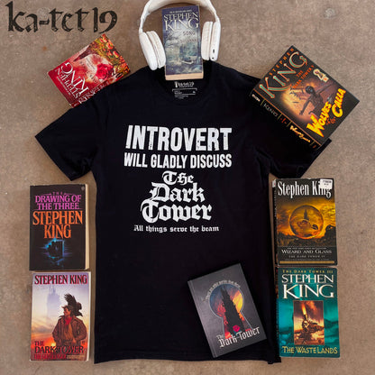 Black t-shirt with 'Introvert will gladly discuss The Dark Tower' text, surrounded by Stephen King books on a concrete surface.