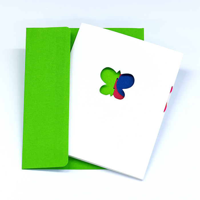 Minimalist greeting card with a butterfly-shaped cutout on a white cover, paired with a bright green envelope in a clean modern stationery presentation.