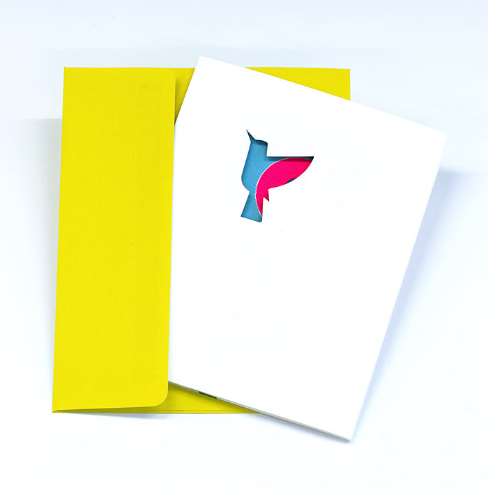 Minimalist greeting card with a hummingbird-shaped cutout on a white cover, paired with a bright yellow envelope in a clean modern stationery presentation.