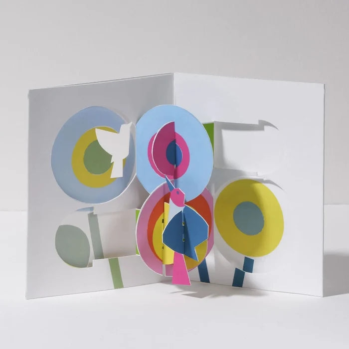 Open 3D pop-up greeting card featuring colorful abstract flowers and birds in bright blue, pink, yellow, green, and white, displayed in a bold modern paper art design.