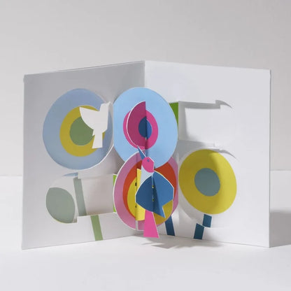 Open 3D pop-up greeting card featuring colorful abstract flowers and birds in bright blue, pink, yellow, green, and white, displayed in a bold modern paper art design.