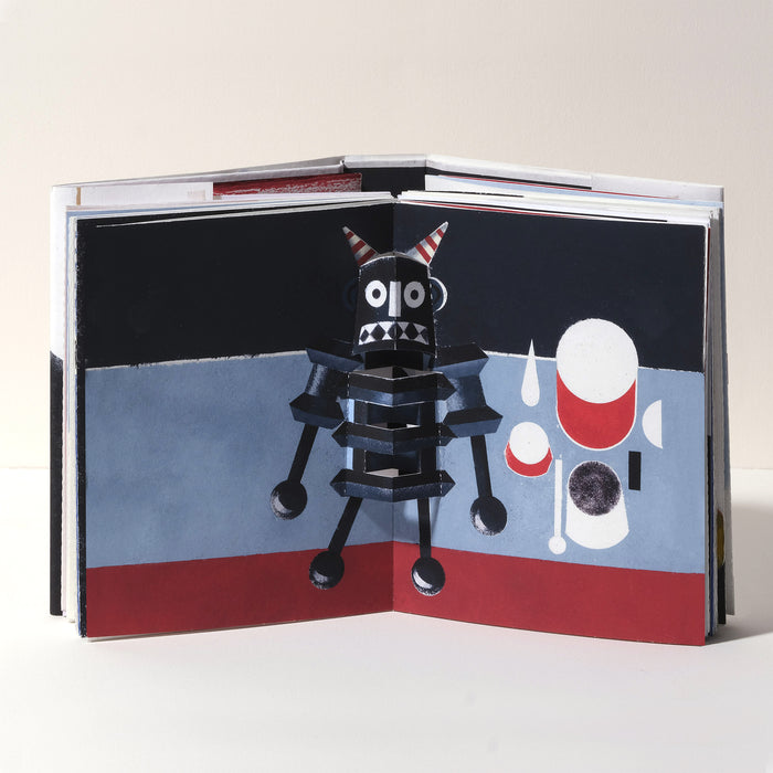 Open art book featuring a playful 3D pop-up devil-like character in black, red, and white, set against a bold abstract background with geometric shapes in a modern graphic style.