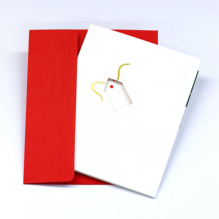 Minimalist Christmas greeting card with a small gift tag illustration on a white cover, paired with a bright red envelope in a clean festive stationery presentation.