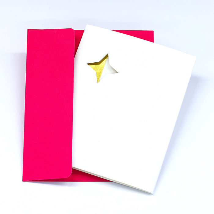 Minimalist Christmas greeting card with a gold star detail on a white cover, paired with a bright pink envelope in a clean festive stationery presentation.