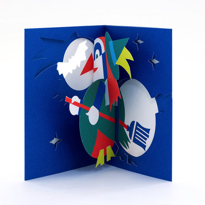 Open 3D pop-up Halloween card featuring a colorful witch flying on a broomstick against a deep blue night sky with stars and a full moon in a playful paper art design.