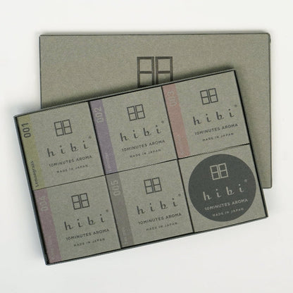 Open Hibi large gray gift box on a white background, displaying six neatly arranged incense matchbook boxes in assorted scents, with the gray Hibi box lid placed behind.