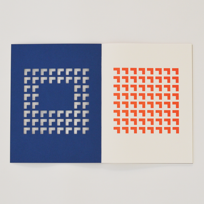 Open TÄT-TAT designer notebook with blue die-cut cover revealing orange geometric pattern on the inner page, modern creative notebook for writing, sketching, and journaling.