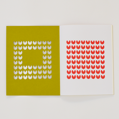 Open TÄT-TAT designer notebook with yellow die-cut cover revealing red geometric pattern on the inner page, modern creative notebook for writing, sketching, and journaling.