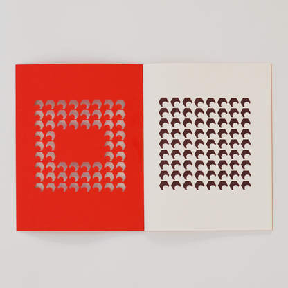 Open TÄT-TAT designer notebook with red die-cut cover revealing brown geometric pattern on the inner page, modern creative notebook for writing, sketching, and journaling.