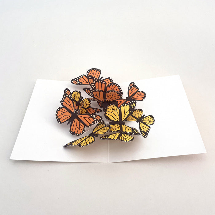 Open 3D pop-up greeting card featuring a cluster of orange and yellow monarch butterflies on a white card base, elegant paper art card for birthdays, celebrations, and nature lovers.