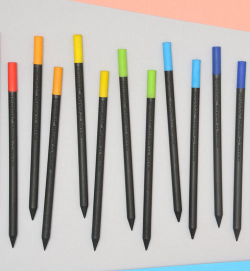 Set of Perpetua recycled graphite pencils with colorful eraser caps in red, orange, yellow, green, and blue, modern eco-friendly Italian stationery arranged on a minimalist background.