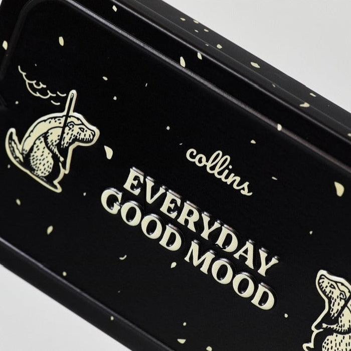 Close-up of a black Collins Everyday Good Mood incense tin with cream lettering, playful illustrated graphics, and speckled details in a bold modern home fragrance design.