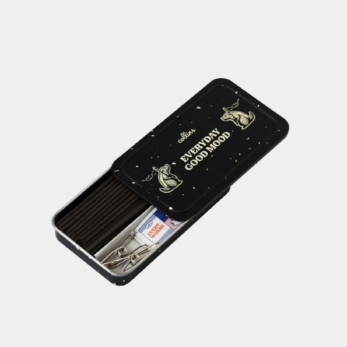 Open black Collins Everyday Good Mood incense tin with dark incense sticks, metal clip holders, and compact accessories, stylish minimalist home fragrance set on a clean white background.