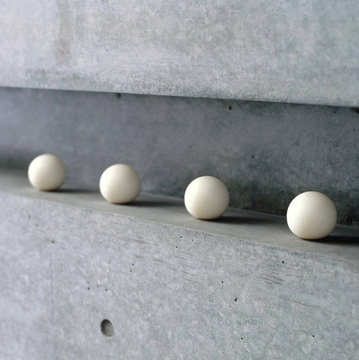 Minimalist white spherical soaps arranged in a row on a concrete shelf, modern decorative soap bars for contemporary bathroom or interior styling.