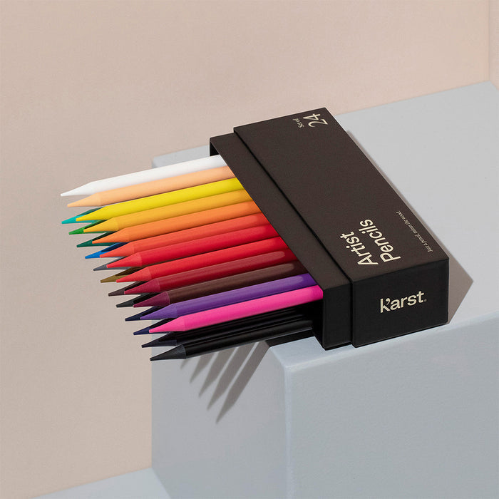 Karst Artist Colored Pencils set of 24 partially sliding out of black storage box, woodless colored pencil set with vibrant colors displayed on pedestal for drawing, sketching, and art supplies.